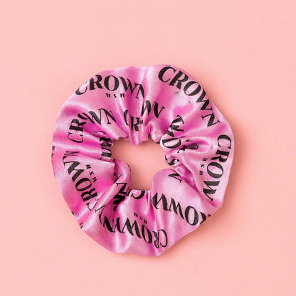 Satin Scrunchie in soft pink with CROWN WASH logo, perfect for styling hair and reducing frizz.