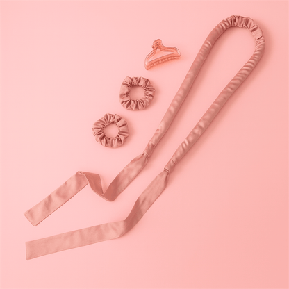 Heatless Curl Kit featuring a silky satin tool, hair scrunchies, and hair clip on a pink background.